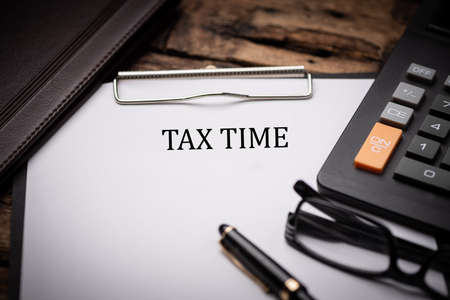 Tax Time text on Document and gavel isolated on wooden office desk close up