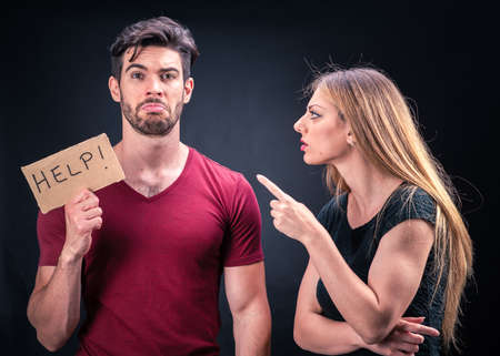 young couple with HELP sign isolated on dark background