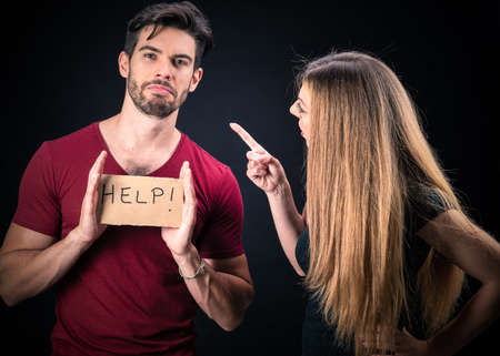 young couple with HELP sign isolated on dark backgroundの写真素材