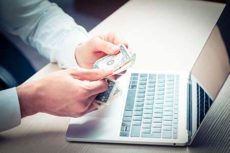 Male hand holing money dollar bill on wood table.business investment concepts close up