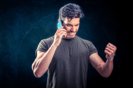 Young Successful Man Talking Cell Phone isolated on dark backgroundの写真素材