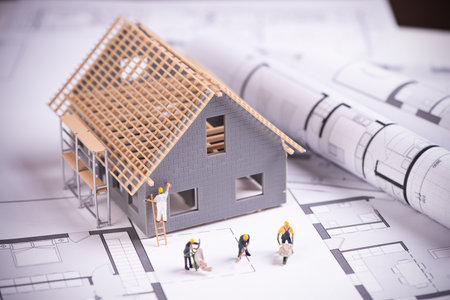 House under construction on blueprints close up. Building project concept