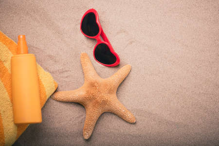 Orange tube of sun protection lotion in the sand on a beach. Close up