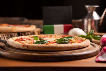 Pizza margarita topped with fresh basil leaves on rustic tableの写真素材