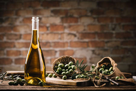 Olive oil with fresh olives on rustic wood close upの写真素材