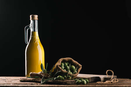 Olive oil with fresh olives on rustic wood close upの写真素材