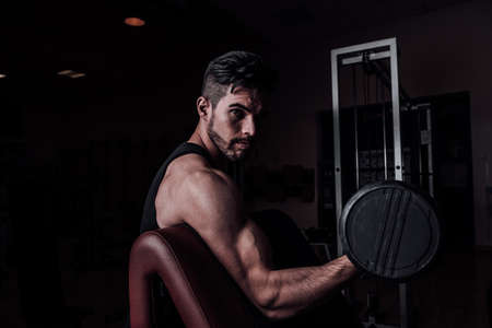 Muscular man working out in gym doing exercises with dumbbells at biceps Close upの写真素材