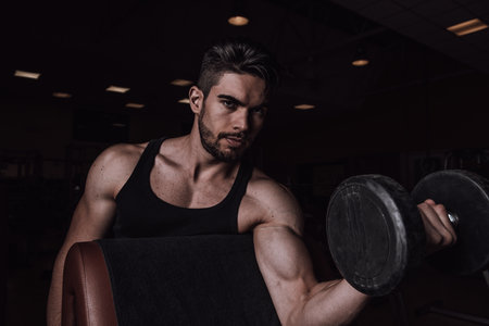 Muscular man working out in gym doing exercises with dumbbells at biceps Close upの写真素材