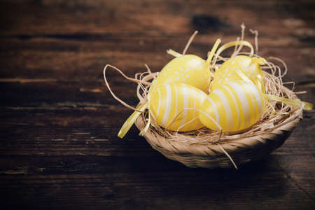Easter eggs in the basket of wooden boards close up
