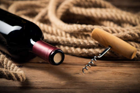 Red wine bottle and corkscrew over rustic wooden table background close upの写真素材