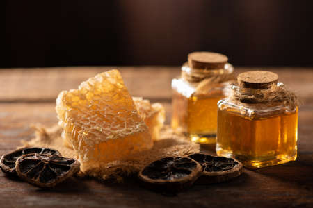 Homemade honey jar with honeycomb on a rustic wooden table close upの写真素材