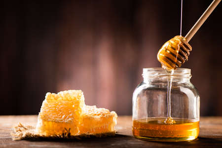 Homemade honey jar with honeycomb on a rustic wooden table close upの写真素材