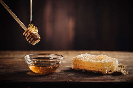 Homemade honey jar with honeycomb on a rustic wooden table close upの写真素材