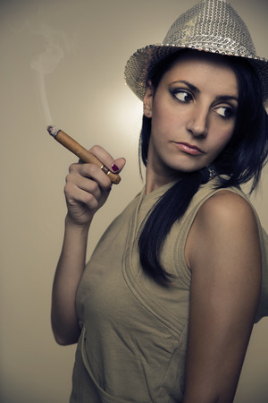sensual woman with shiny hat smoking a cigarの写真素材