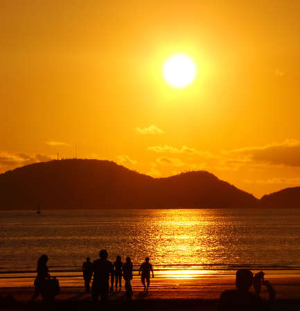 people on the beach under a beautiful golden sunsetの写真素材