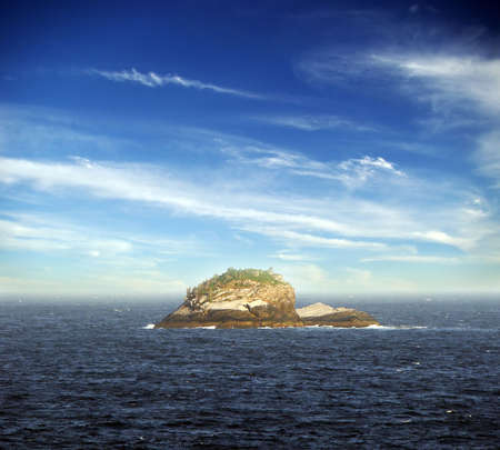 lonely island on the sea under beautiful blue sky and cloudsの写真素材