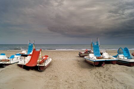 Beach with colorful pedal boats and cloudy skyの写真素材
