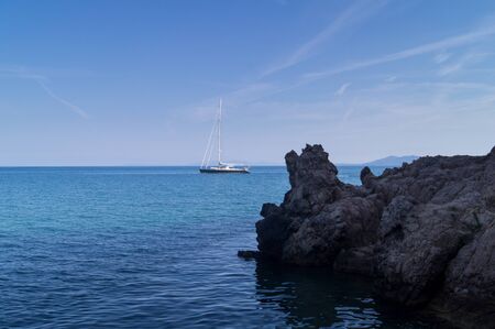 Panorama of the Tuscan sea with a sailboat.
