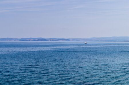 Panorama of the Tuscan sea with a sailboat.