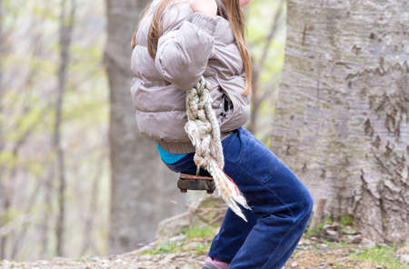 little girl playing on the old swing in the woodsの写真素材