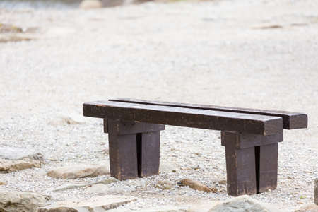 old brown bench on the lake shoreの写真素材