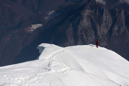 Alpinist walking on a snow ridgeの写真素材