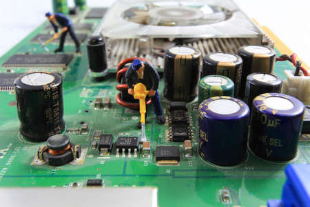 Little workers are repairing the old graphic card.の写真素材