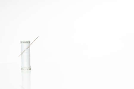 Spool of white thread with sewing needle and measuring tape on white background