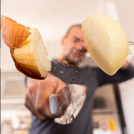 oung man cutting an onion in the air - Close up male hand holding sharp knife preparing a onion salad - People lifestyle and healthy exotic food concept - Focus on male handの写真素材