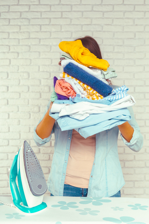 Housewife bringing a huge pile of laundry on the ironing boardの写真素材