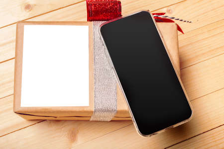 Smart phone and gift on wooden backgroundの写真素材