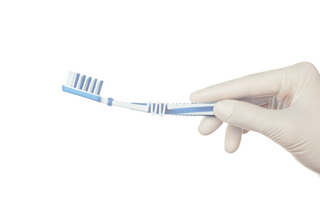 Gloved doctor's hand holding a toothbrushの写真素材