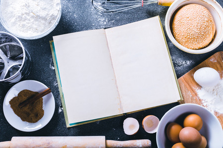 Baking dark background with blank cook book, eggshell, bread, flour, rolling pin. Ingredients for the baking.の写真素材