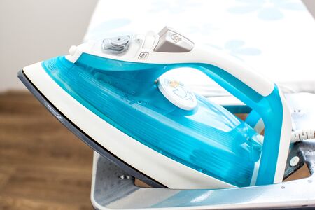 Iron on ironing board on light home interior backgroundの写真素材