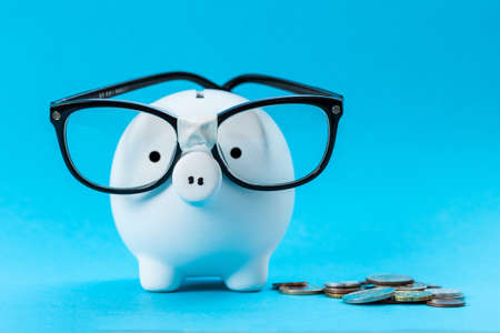 Piggy bank with glasses on blue backgroundの写真素材