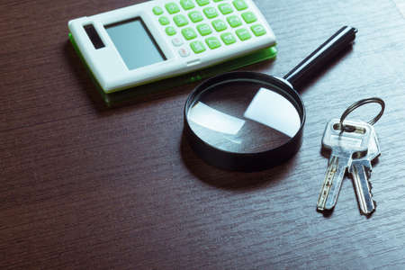 notebook on a brown wooden background with a calculator and magnifying glassの写真素材
