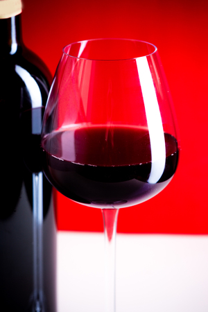 glass of red wine is on the red backgroundの写真素材