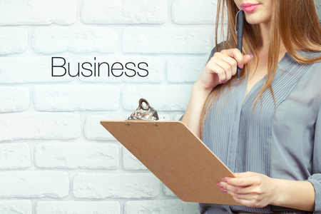 businesswoman with clipboard and pen making notes and standing near textの写真素材