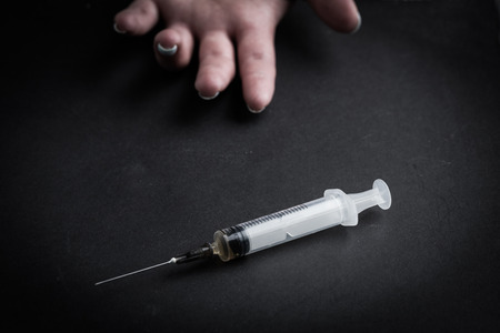 Drug Addict hand with syringe on the floorの写真素材