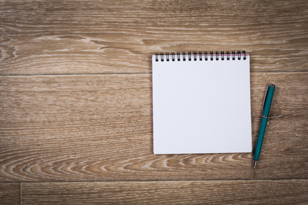 Blank note paper with pen on wood backgroundの写真素材