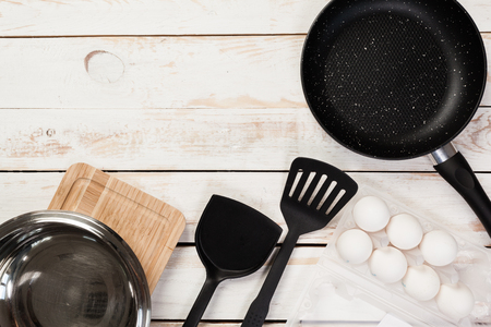 Cast iron pan and other kitchen utensils on wooden table, top viewの写真素材