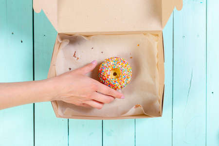 Donuts in box on wooden table. Top view