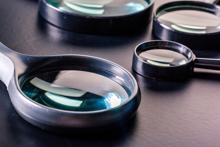 Closeup of magnifying glasses on dark surfaceの写真素材