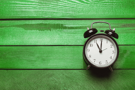 alarm clock on a green wooden tableの写真素材