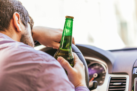 man drinking alcohol while driving the car
