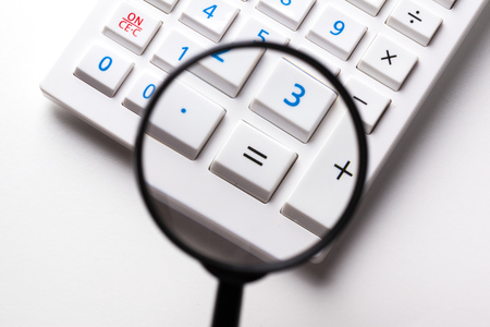 Calculator with a magnifying glass on a white backgroundの写真素材