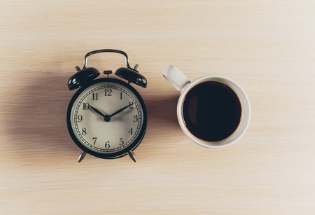 Coffee with alarm clock on wooden table