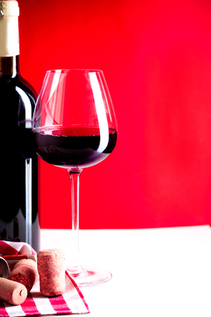 glass of red wine is on the red backgroundの写真素材