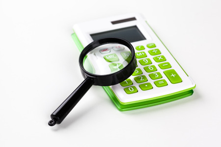 Calculator with a magnifying glass on a white backgroundの写真素材
