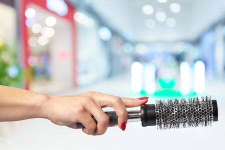 Female hand holding barber comb in cosmetic storeの写真素材